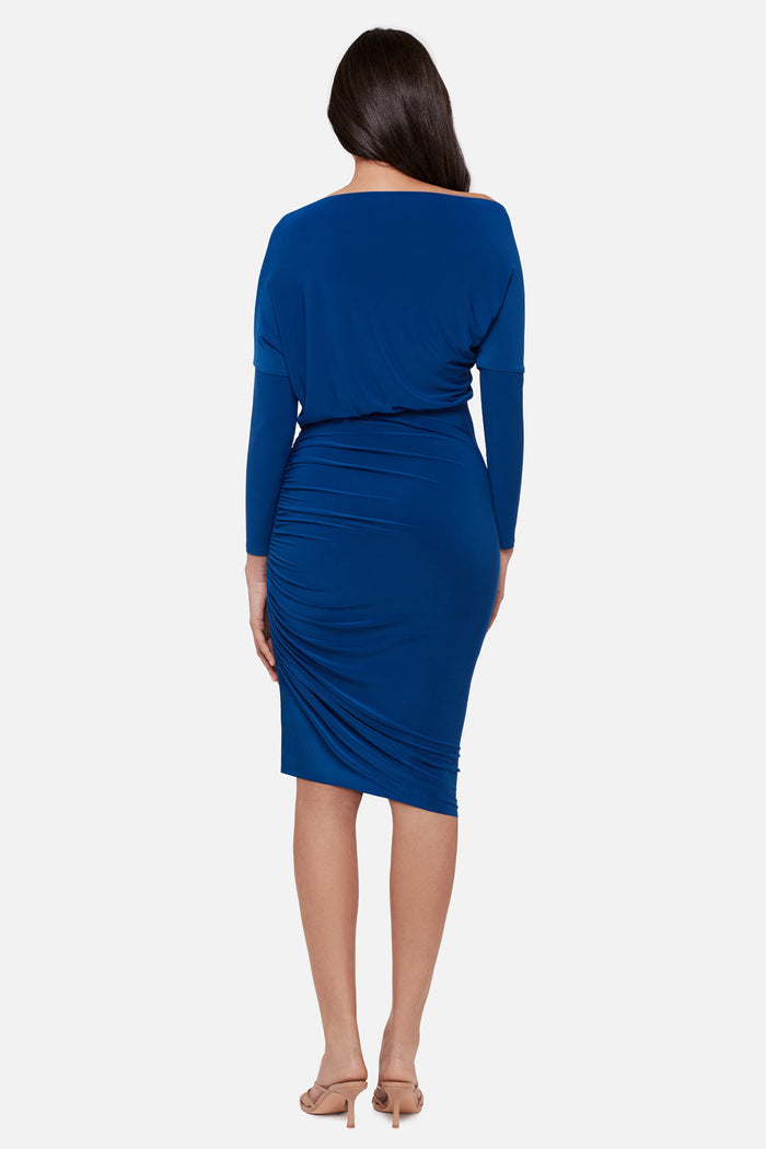 Woman turned away wearing a blue long sleeve mid length dress
