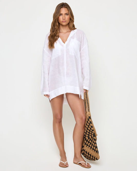 Front view of a model wearing the LSPACE Oasis Tunic in white, an oversized semi-sheer linen beach shirt with long sleeves, an open collar, and a relaxed cover-up silhouette.