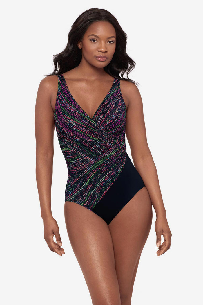 Woman wearing a multicolor abstract print one-piece swimsuit with a black panel at the hip