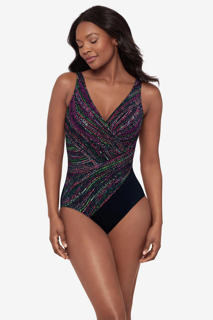 Woman wearing a multicolor abstract print one-piece swimsuit with a black panel at the hip