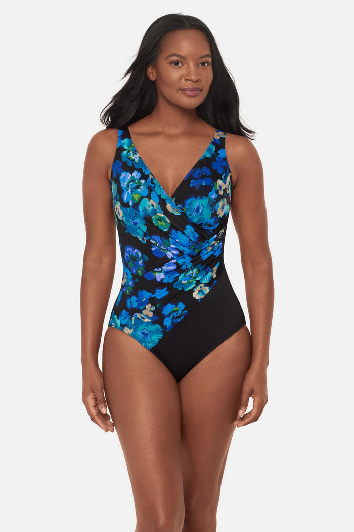 Woman wearing a black and blue floral printed one-piece swimsuit with a black panel on the side