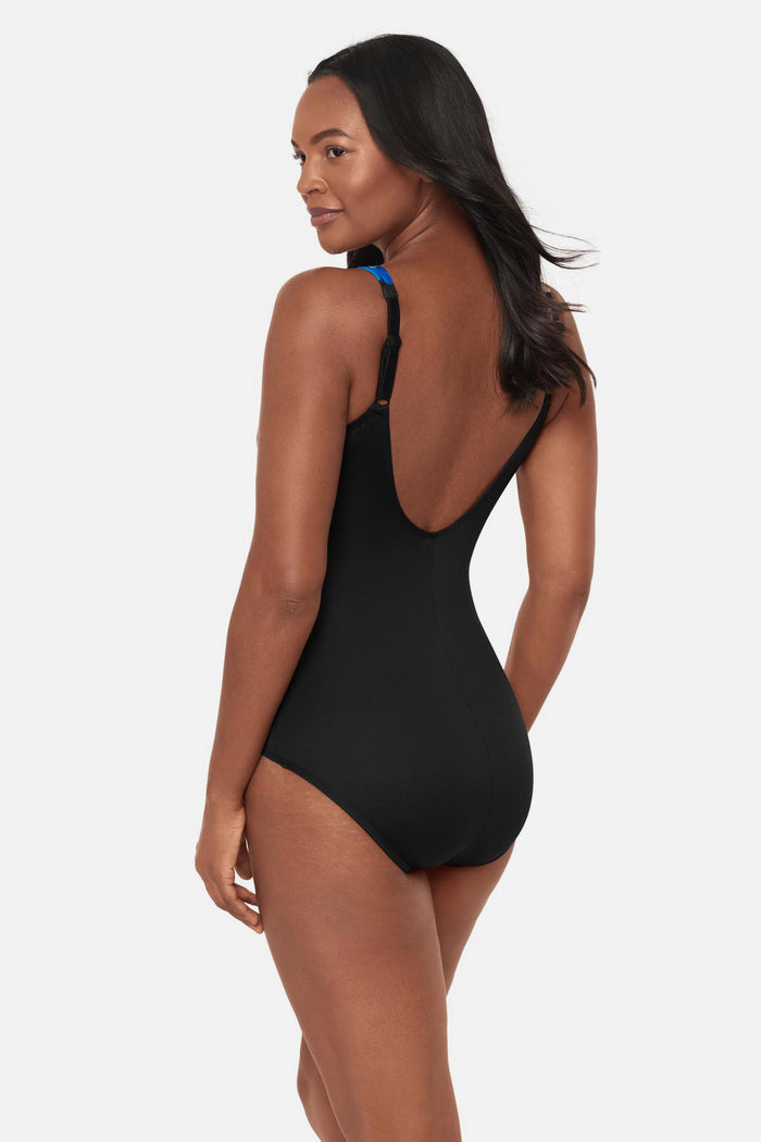 Woman turned left wearing a black and blue floral printed one-piece swimsuit