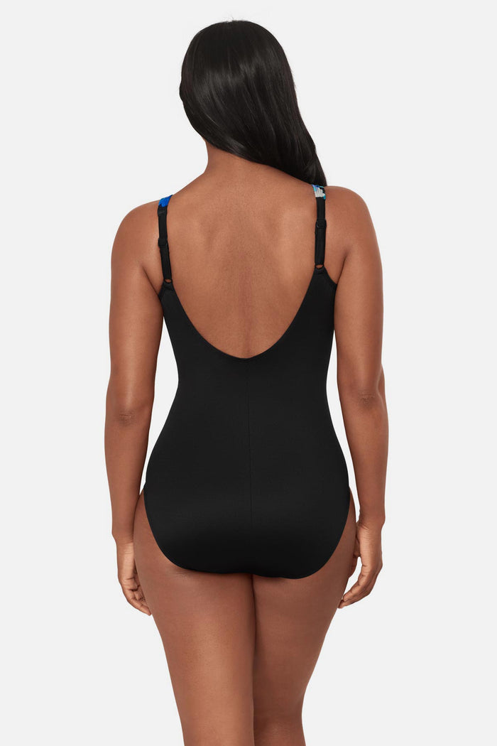 Woman turned away wearing a black and blue floral printed one-piece swimsuit