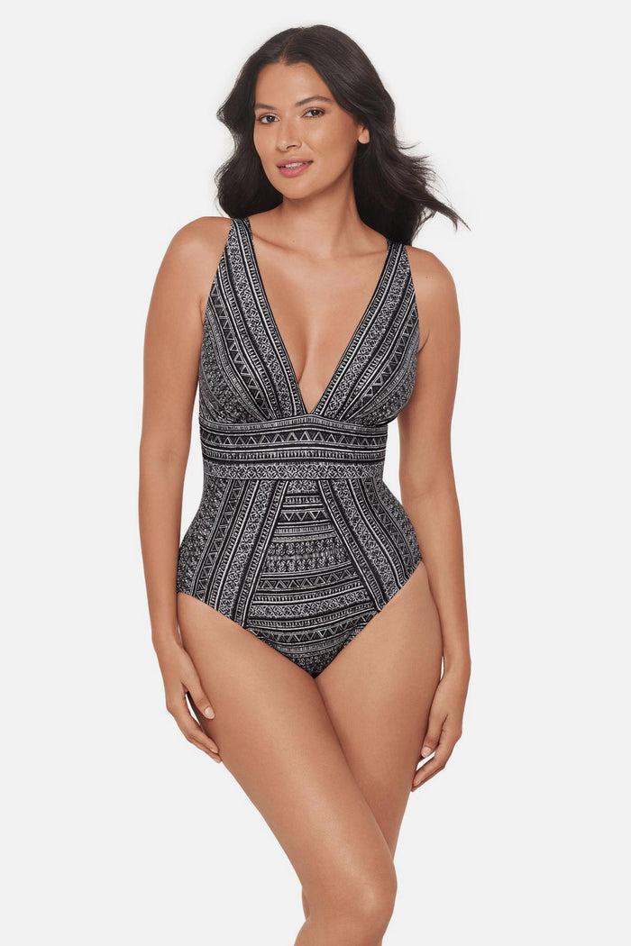 Woman wearing a black and white geometric pattern one-piece swimsuit with V neckline