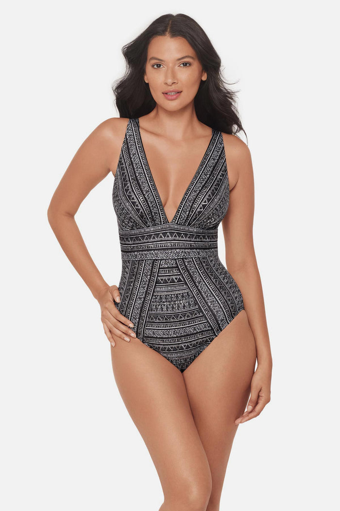Woman wearing a black and white geometric pattern one-piece swimsuit with V neckline