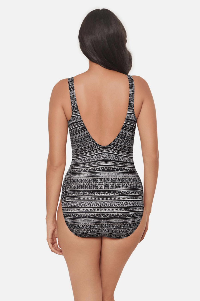 Woman turned away wearing a black and white geometric pattern one-piece swimsuit with V neckline