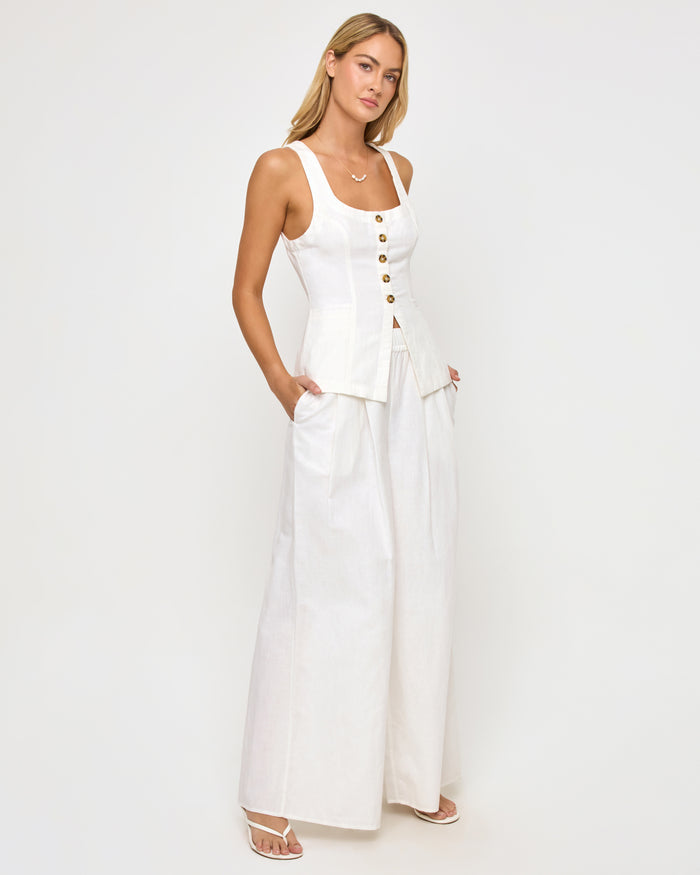 Side view of a model wearing the LSPACE white Palma Pant, high-rise wide-leg trousers with a relaxed fit, styled with a matching white button-front sleeveless top on a neutral studio background.