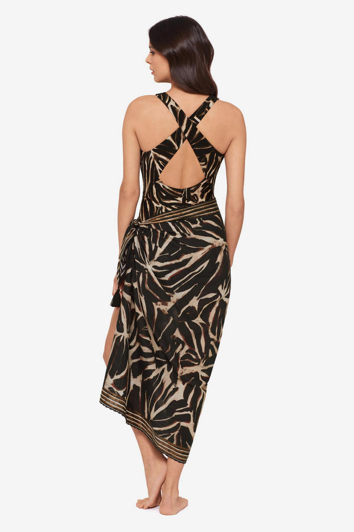 Woman turned away wearing a brown leaf printed one-piece swimsuit with a matching swim cover up