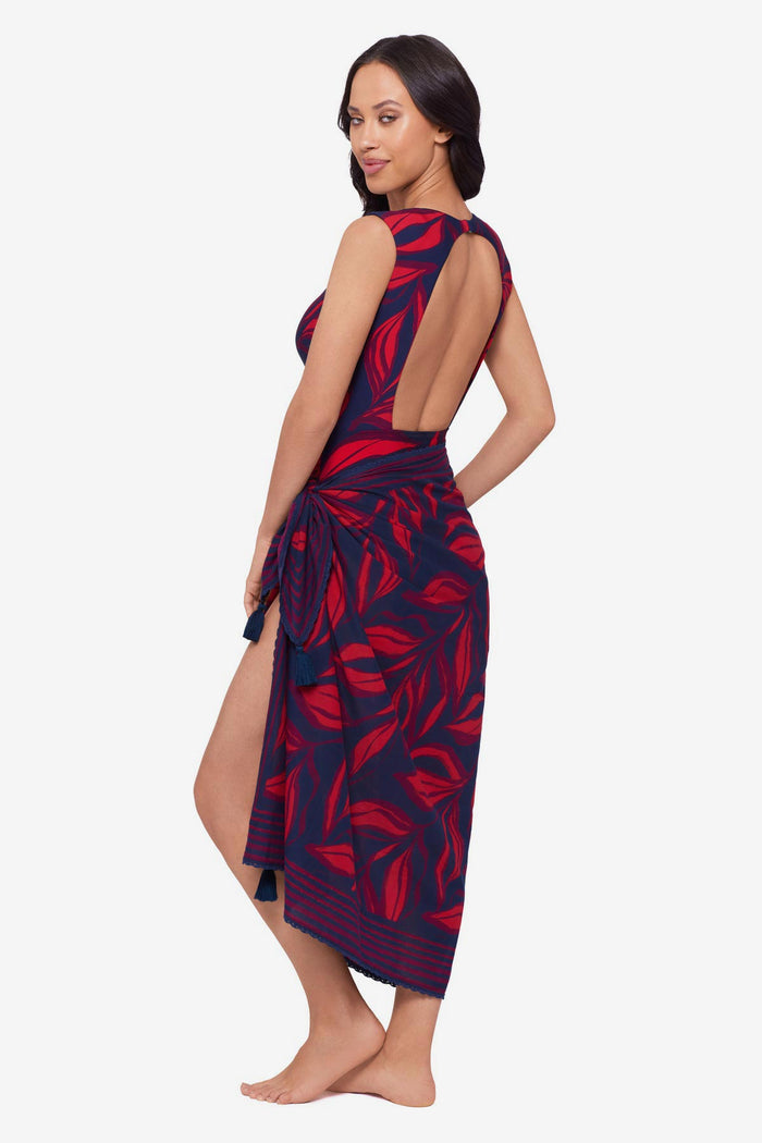 Woman turned left wearing a red leaf print one-piece swimsuit with a matching swim cover up