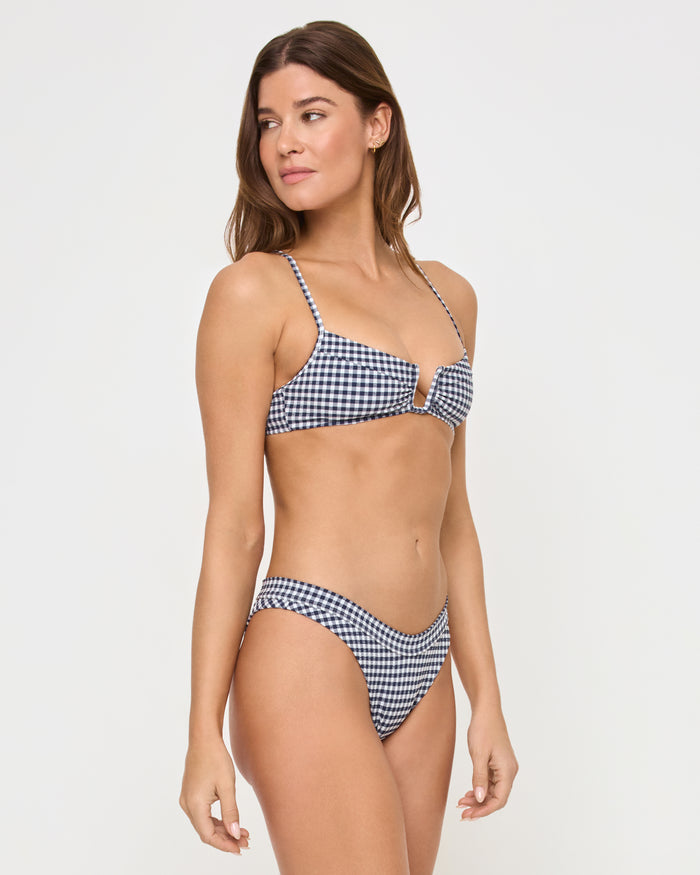 Three-quarter side view of a model wearing the LSPACE atta girl gingham Peyton Bikini Top in navy and white gingham check with spaghetti straps, paired with matching gingham Dolce Bikini Bottoms.