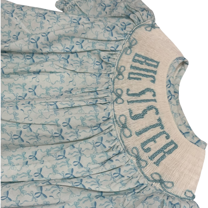 Close-up of “BIG SISTER” smocking and blue bow print