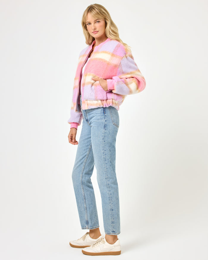 Side view of a model wearing the LSPACE Quinn Jacket in point dume plaid, showing the fuzzy plaid texture and relaxed bomber silhouette with ribbed cuffs, paired with wide-leg jeans.