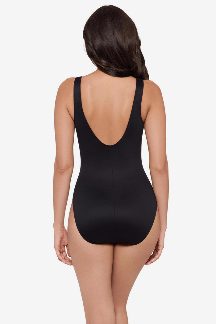 Woman turned away wearing a black and brown printed one-piece swimsuit with a scoop back