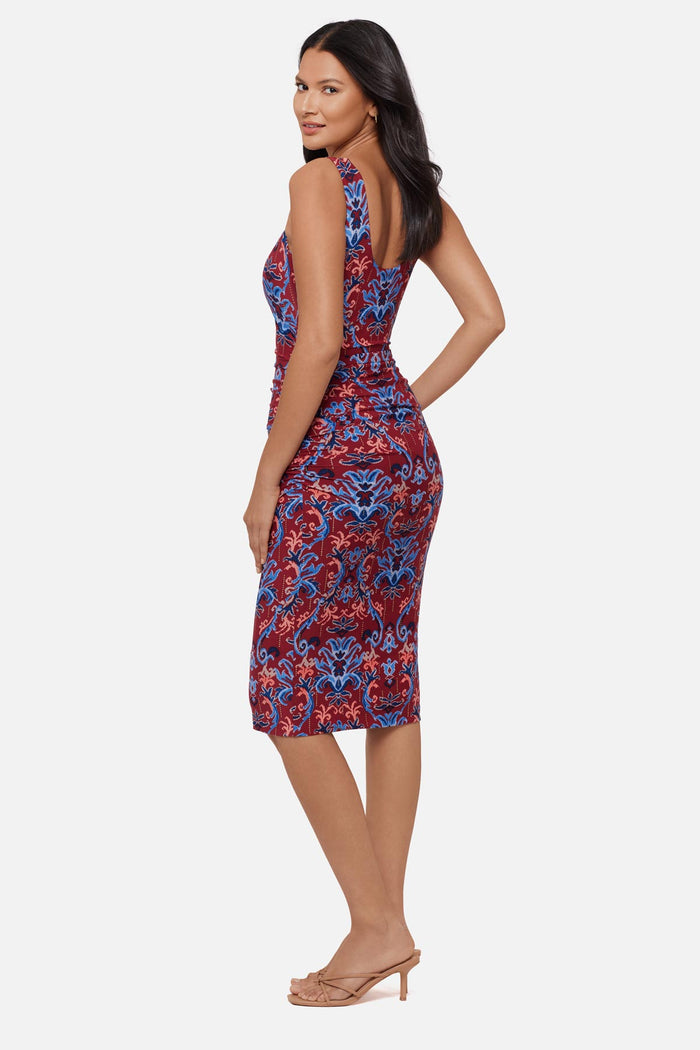 Woman turned left wearing a red and blue paisley-esque sleeveless mid length dress