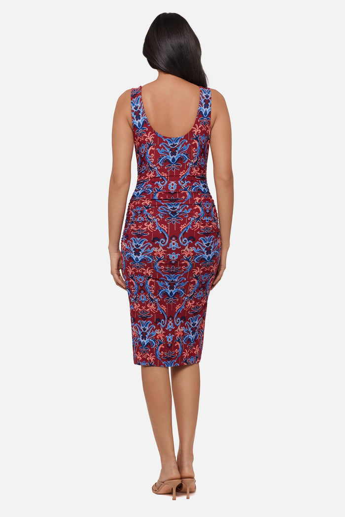 Woman faced away wearing a red and blue paisley-esque sleeveless mid length dress