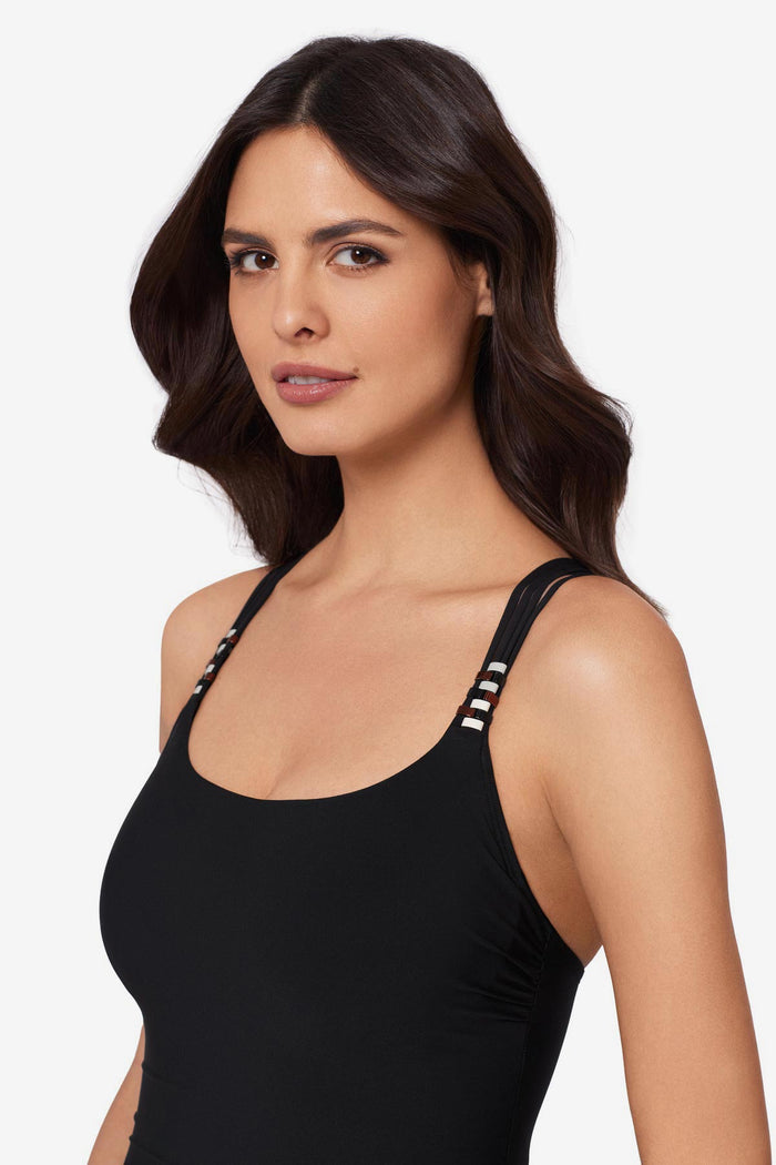Close up of woman wearing a black one-piece swimsuit with beads on the straps