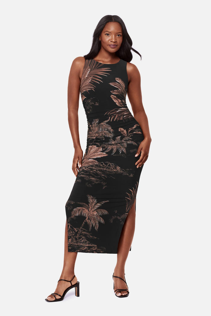 Woman wearing a sleeveless full-length dress with a brown and shite detailed palm tree print