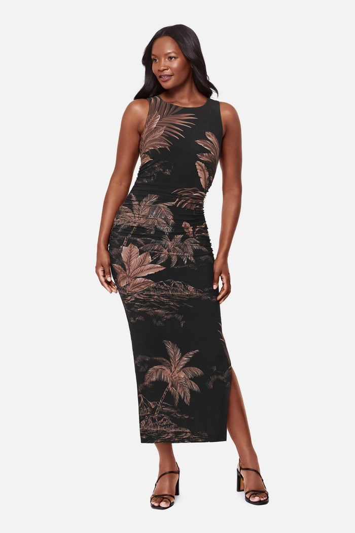 Woman wearing a sleeveless full-length dress with a brown and shite detailed palm tree print