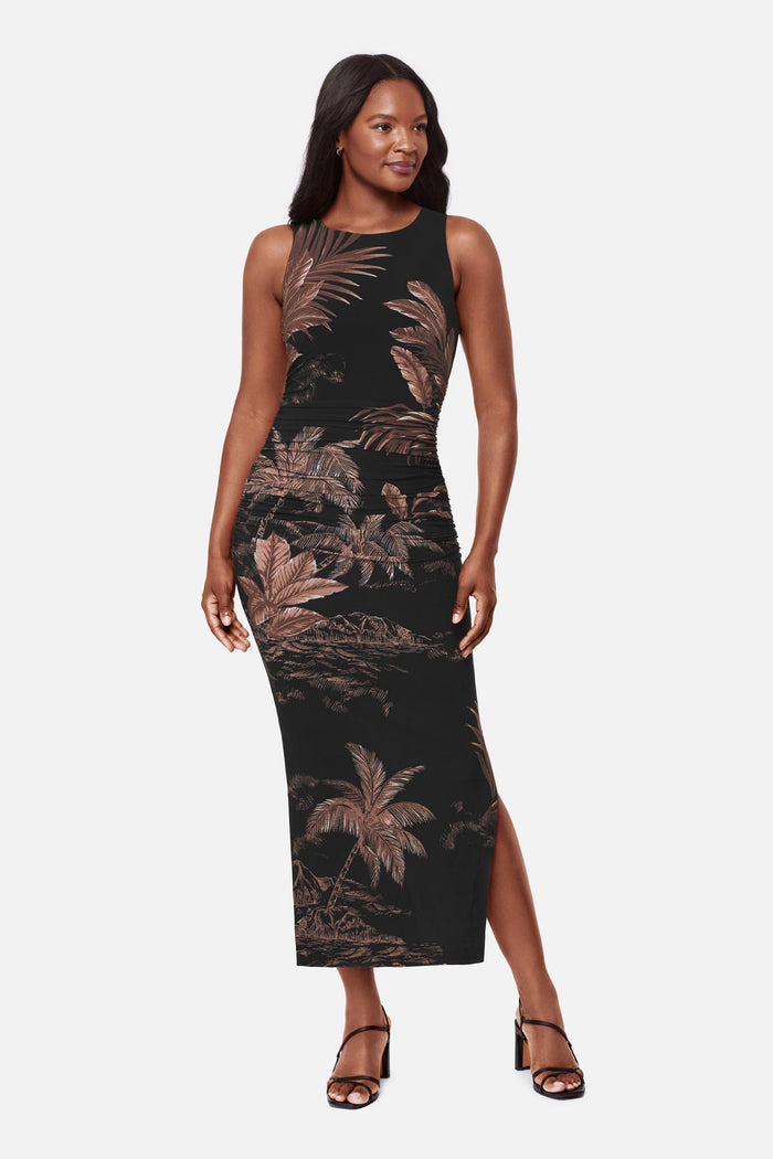 Woman wearing a sleeveless full-length dress with a brown and shite detailed palm tree print