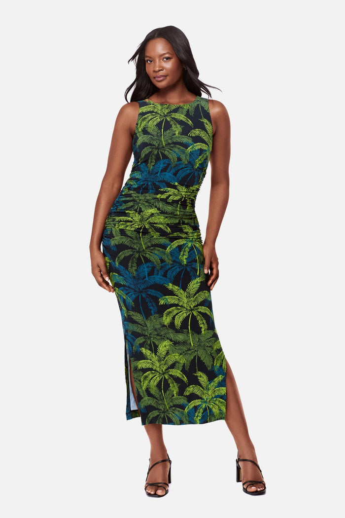 Woman wearing a sleeveless full-length dress with a blue and green palm tree print