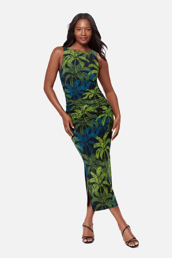 Woman wearing a sleeveless full-length dress with a blue and green palm tree print