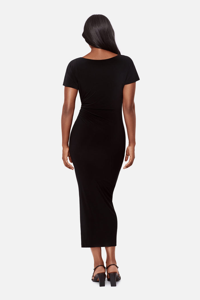 Woman turned away wearing a black short sleeve full length dress
