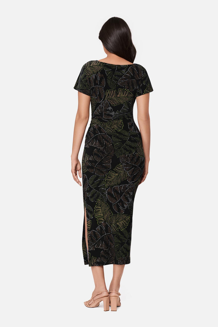 Woman turned away wearing a short sleeve full-length dress with a dotted palm leaf print