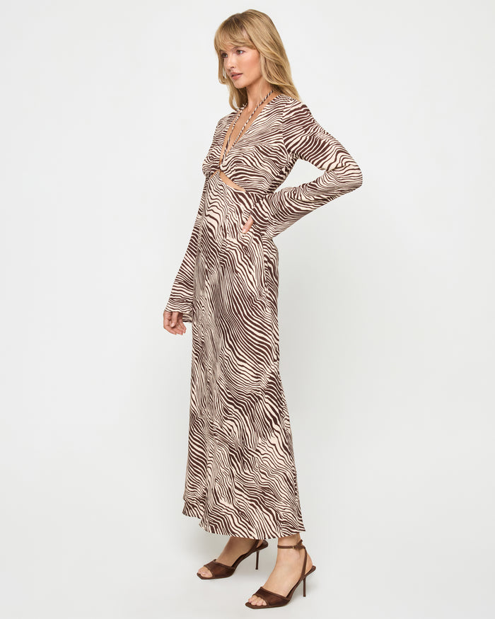 Side view of a model wearing the LSPACE Say When Maxi Dress in animal, showing the long-sleeve silhouette and flowing maxi length in a warm brown and beige zebra print.
