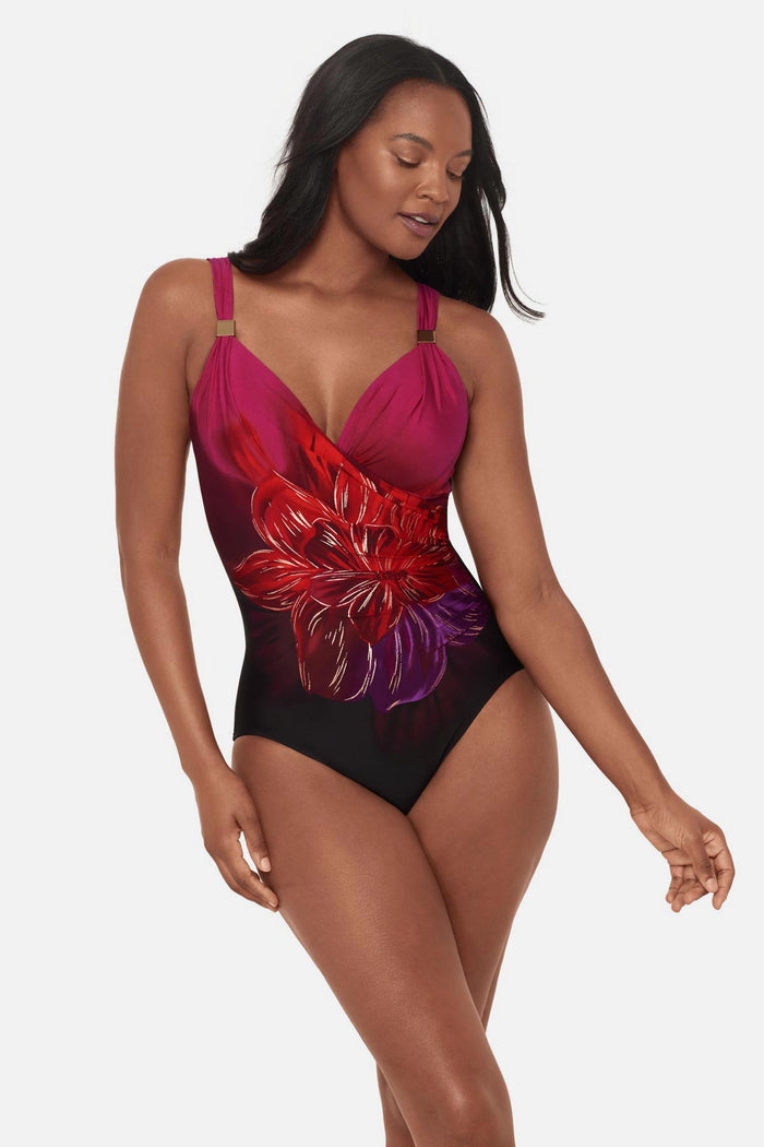 Woman wearing a red, pink and purple floral printed one-piece swimsuit