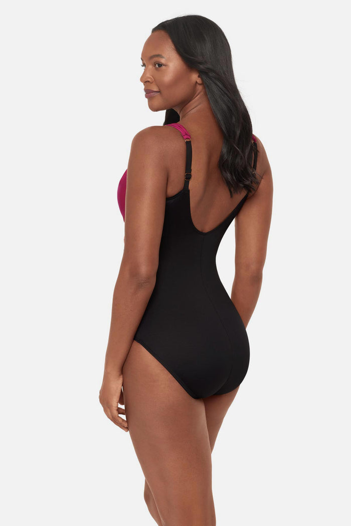 Woman turned left wearing a red, pink and purple floral printed one-piece swimsuit