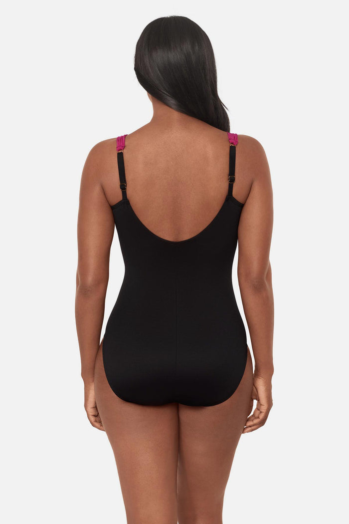Woman turned away wearing a red, pink and purple floral printed one-piece swimsuit