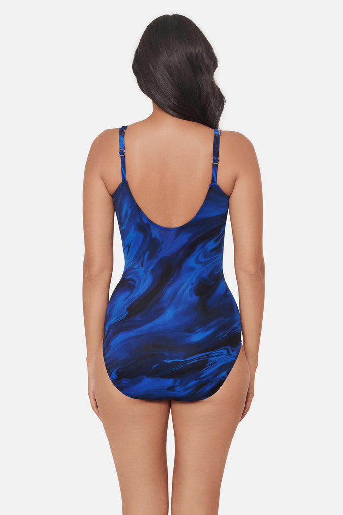 Woman wearing a blue and gold oil slick-esque printed one-piece swimsuit