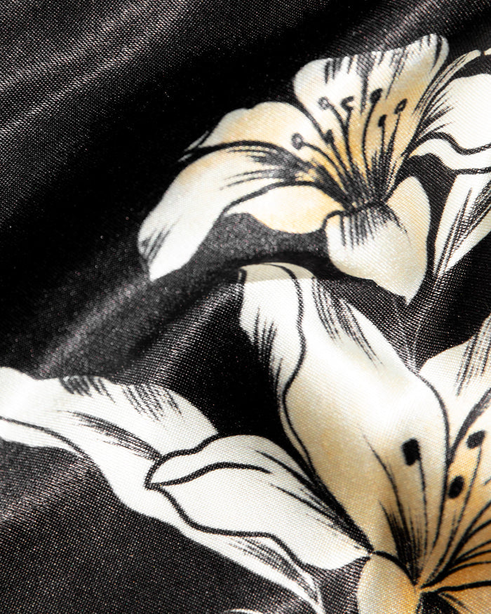 Close-up of the LSPACE So Fine Mini in petal to the metal, highlighting the black satin fabric with a cream and gold lily floral print.
