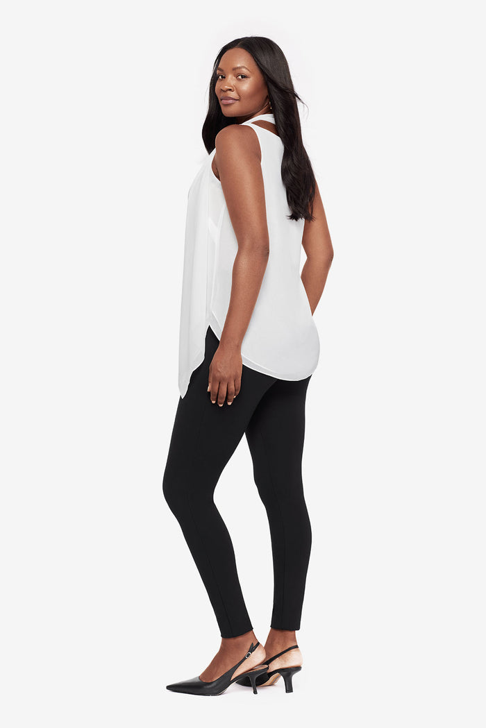 Woman turned left wearing a white tunic blouse with black leggings