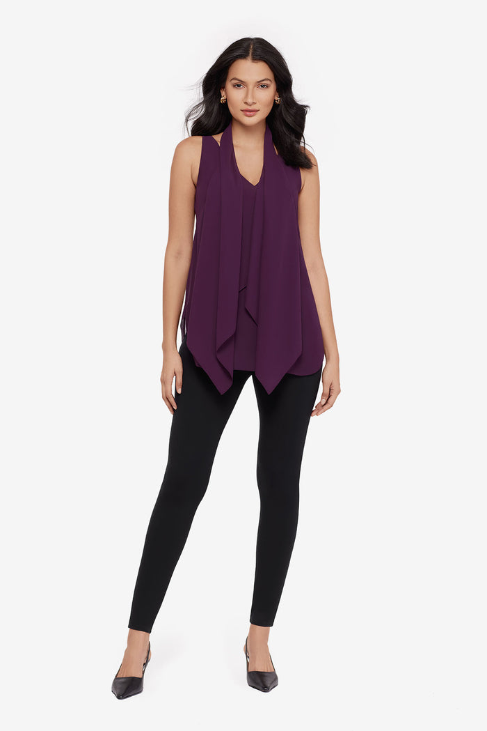 Woman wearing a plum-colored tunic blouse with black leggings