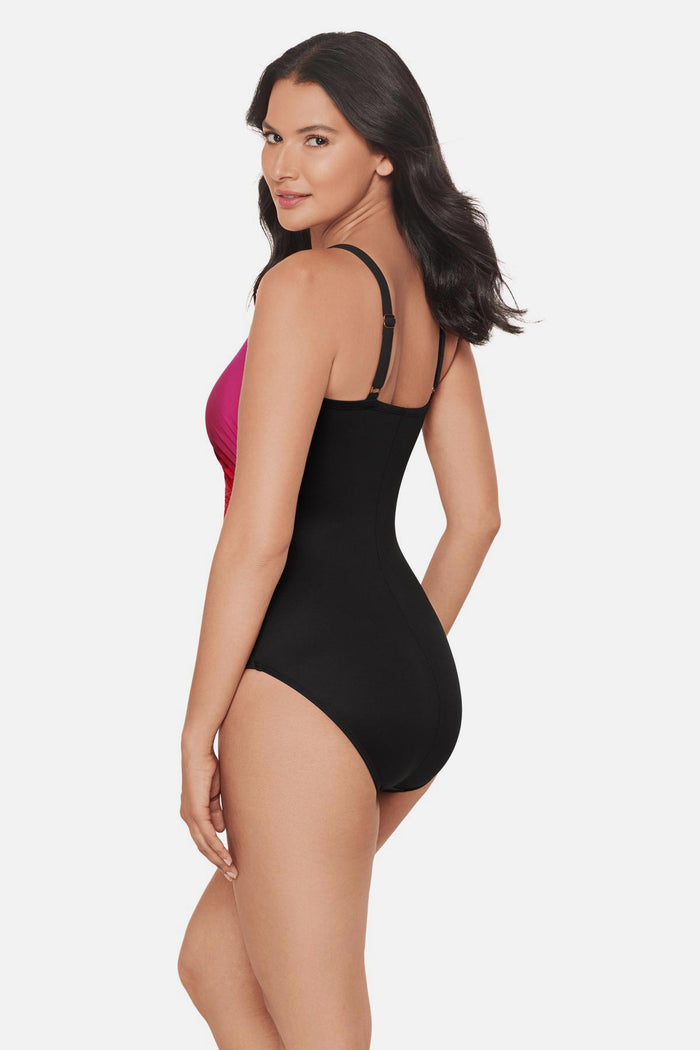 Woman turned left wearing a red, pink and purple floral printed one-piece swimsuit
