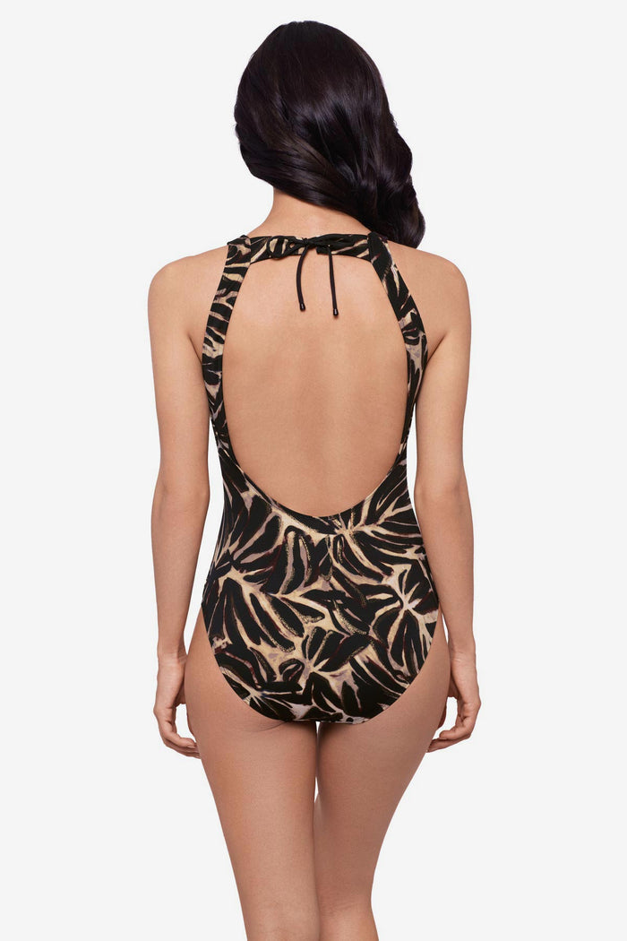 Woman turned away wearing a brown leaf printed one-piece swimsuit
