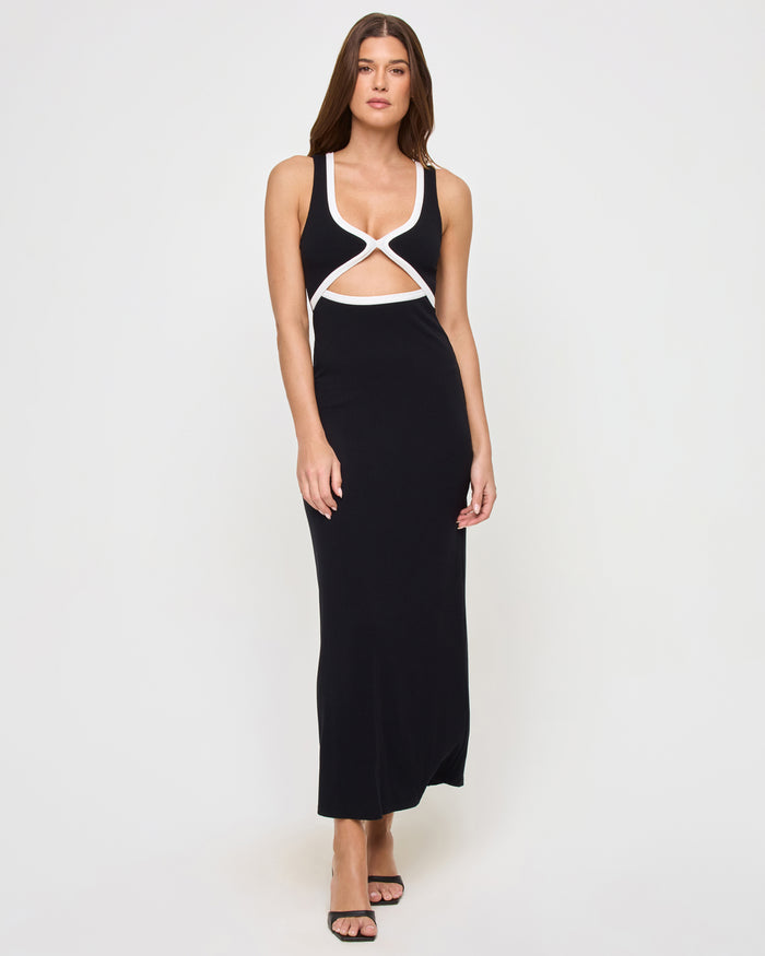 Full-length front view of a model wearing the LSPACE Steph Dress in black-cream, a form-fitting maxi dress with a crossover cut-out bodice trimmed in cream and a sleek black maxi skirt, styled with heeled sandals.