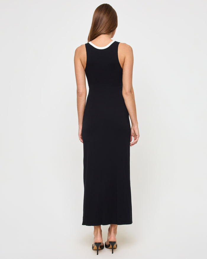 Back view of a model wearing the LSPACE Steph Dress in black-cream, showing the sleeveless black back with cream-trimmed neckline and the form-fitting maxi skirt, styled with heeled pumps.