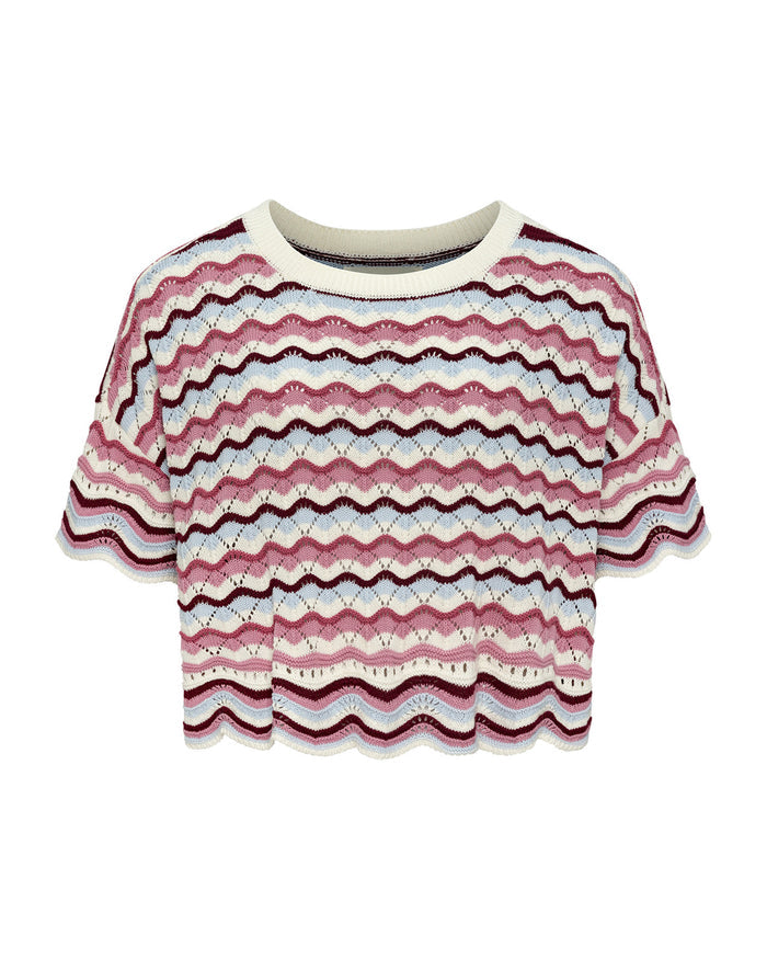 Off-model flat lay of the LSPACE sand in hand Sunchaser Top, an oversized crochet knit short-sleeve crop top with a round neckline and multicolor wavy stripe pattern in pink, blue, and cream, on a white background.