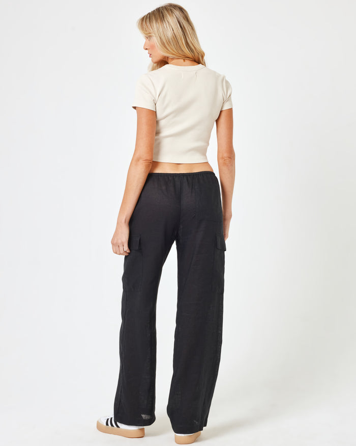 Back view of a model wearing the LSPACE Sundown Cargo Pant in black, showing the back pockets and relaxed-fit silhouette.