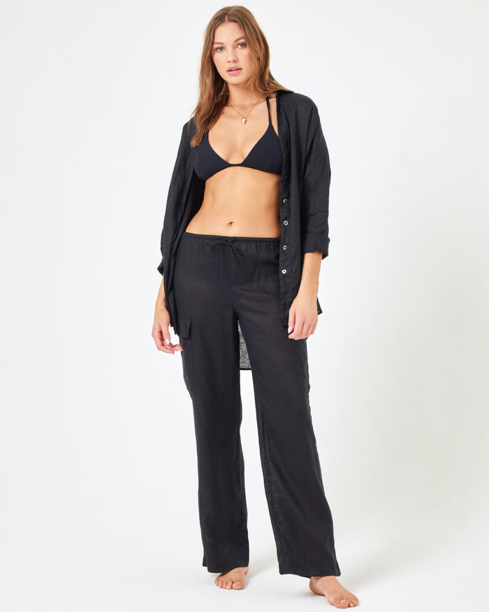 Front view of a model wearing the LSPACE Sundown Cargo Pant in black, showing the full-length look styled with a black swim top.