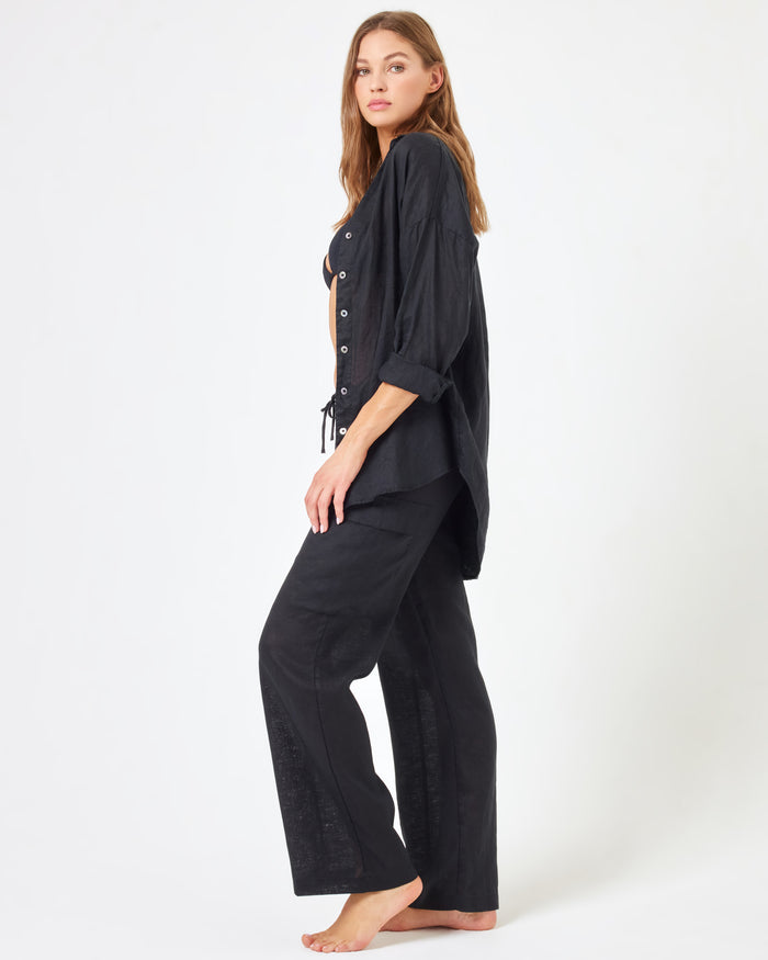 Three-quarter view of a model wearing the LSPACE Sundown Cargo Pant in black, highlighting the cargo pockets and relaxed waistband.