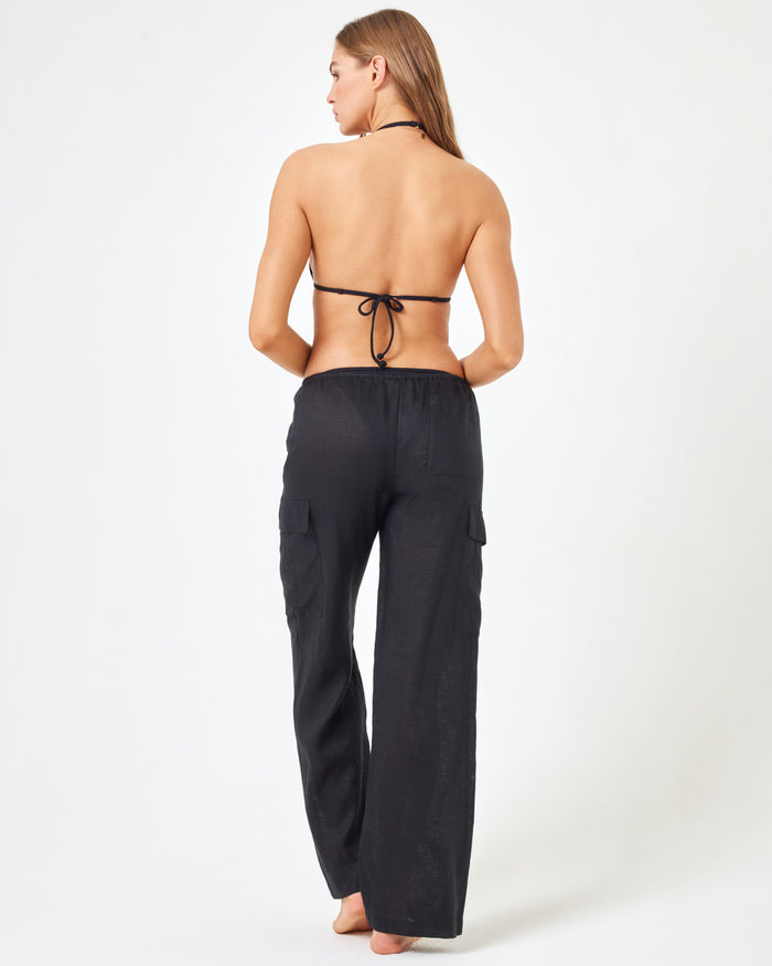 Back view of a model wearing the LSPACE Sundown Cargo Pant in black, showcasing the cargo pocket and straight-leg hem.