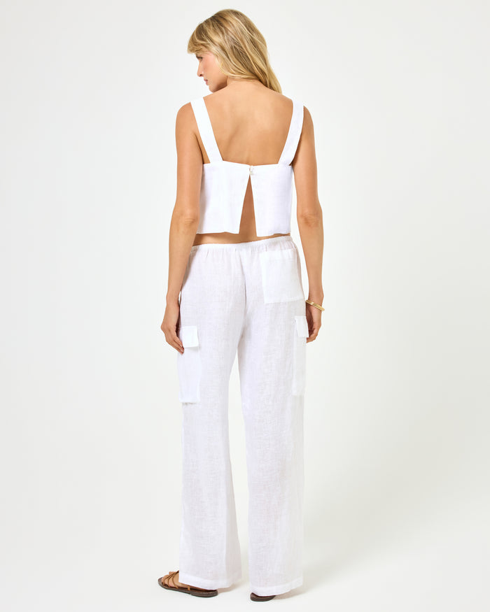 Back view of a model wearing the LSPACE Sundown Cargo Pant in white, wide-leg linen pants with a drawstring waist, paired with a white crop top.