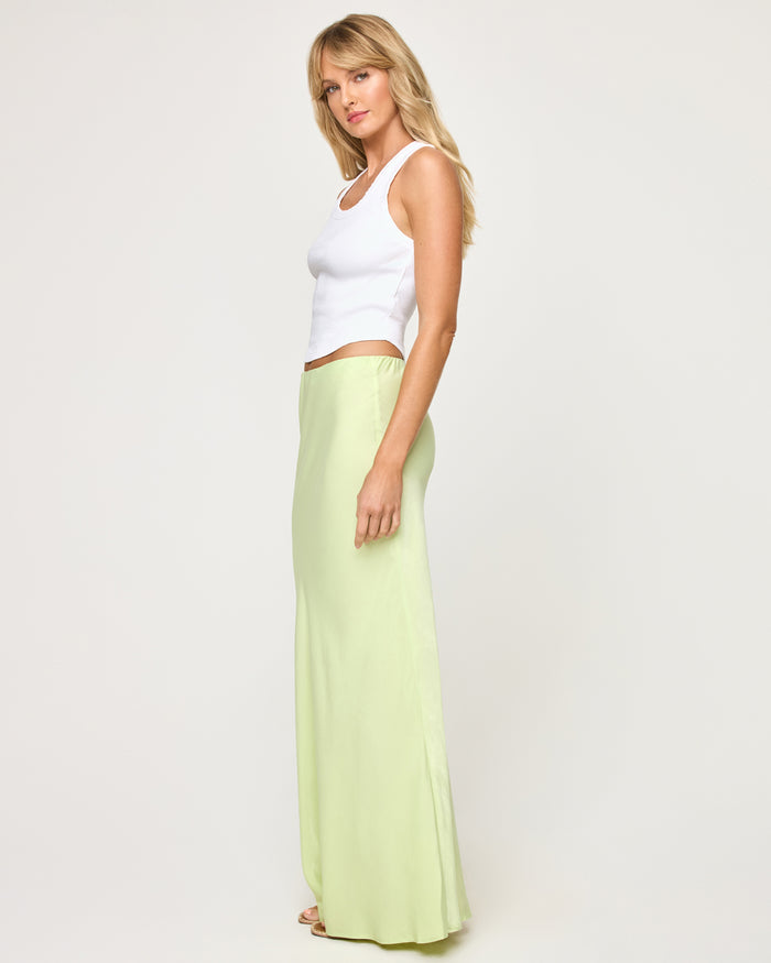 Side view of a model wearing the LSPACE Sweet As Honey Skirt in honeydew, showing the smooth satin silhouette and floor-length hemline.
