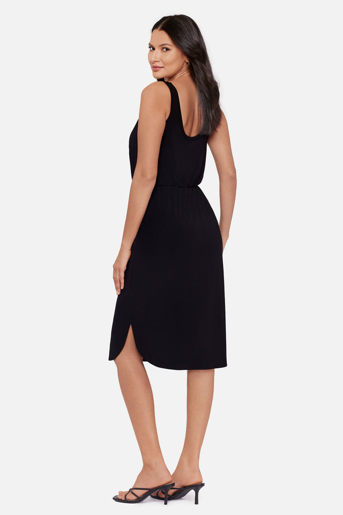 Woman faced left wearing a black sleeveless mid length dress