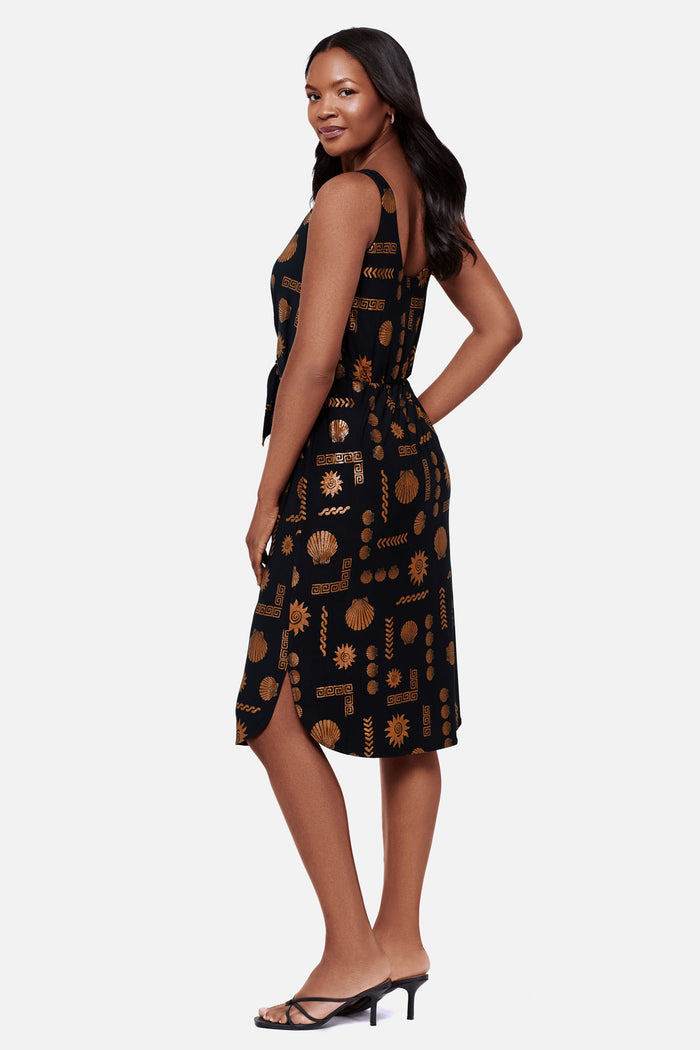 Woman turned left wearing a brown and black shell printed sleeveless mid length dress