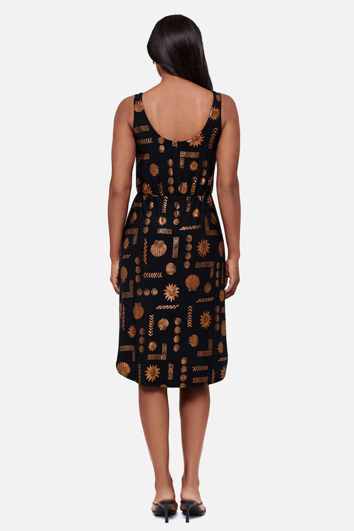 Woman faced away wearing a brown and black shell printed sleeveless mid length dress