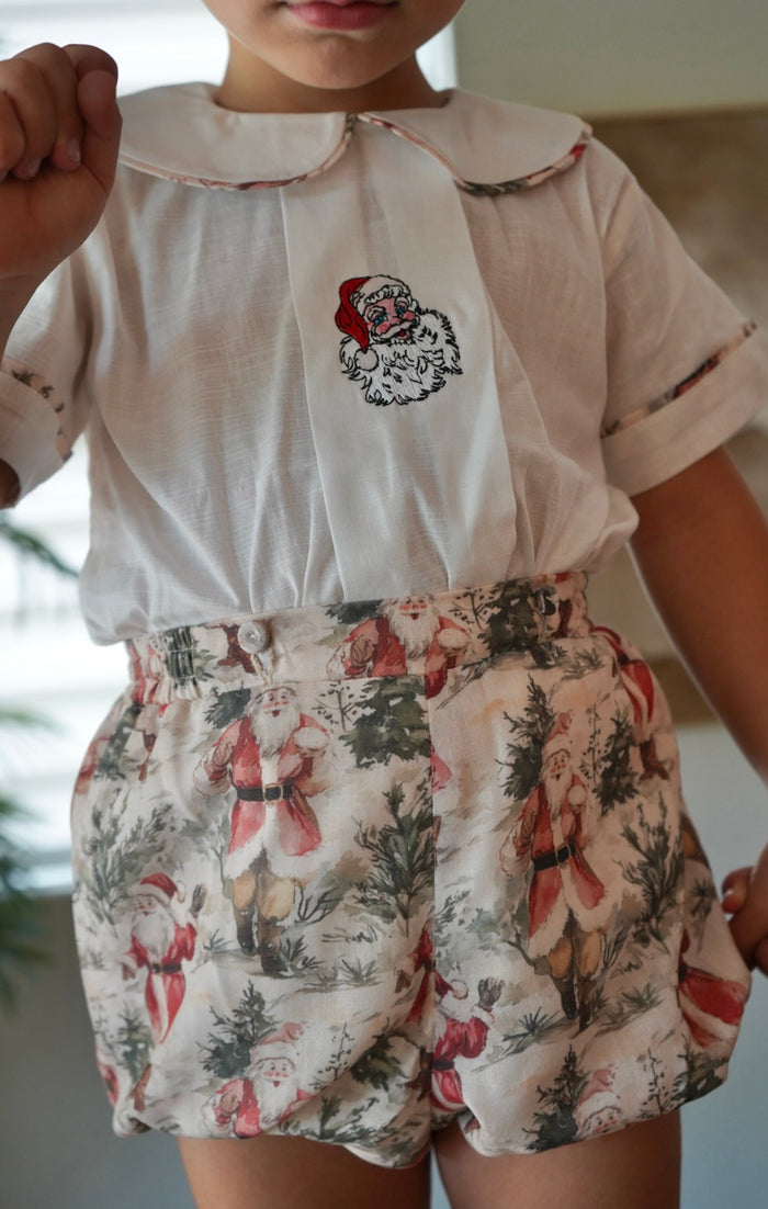 Close-up of boy wearing ivory embroidered shirt and vintage Santa print shorts